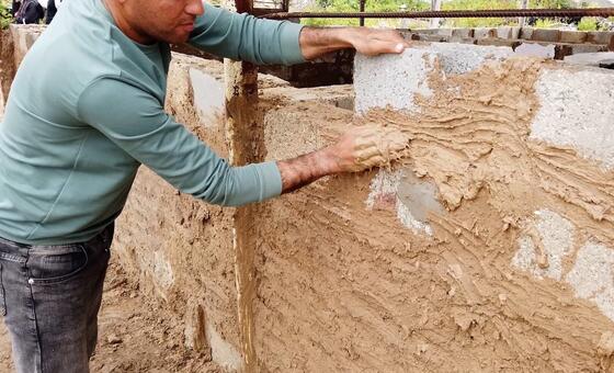 يقوم محمد الجذبة ببناء مأوى لعائلته باستخدام أنقاض منزله المدمر والطين.